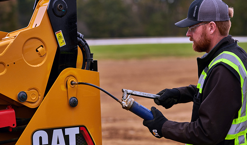 Greasing loader pins on Cat® equipment during daily maintenance check – DIY Caterpillar upkeep to reduce friction and extend machine life